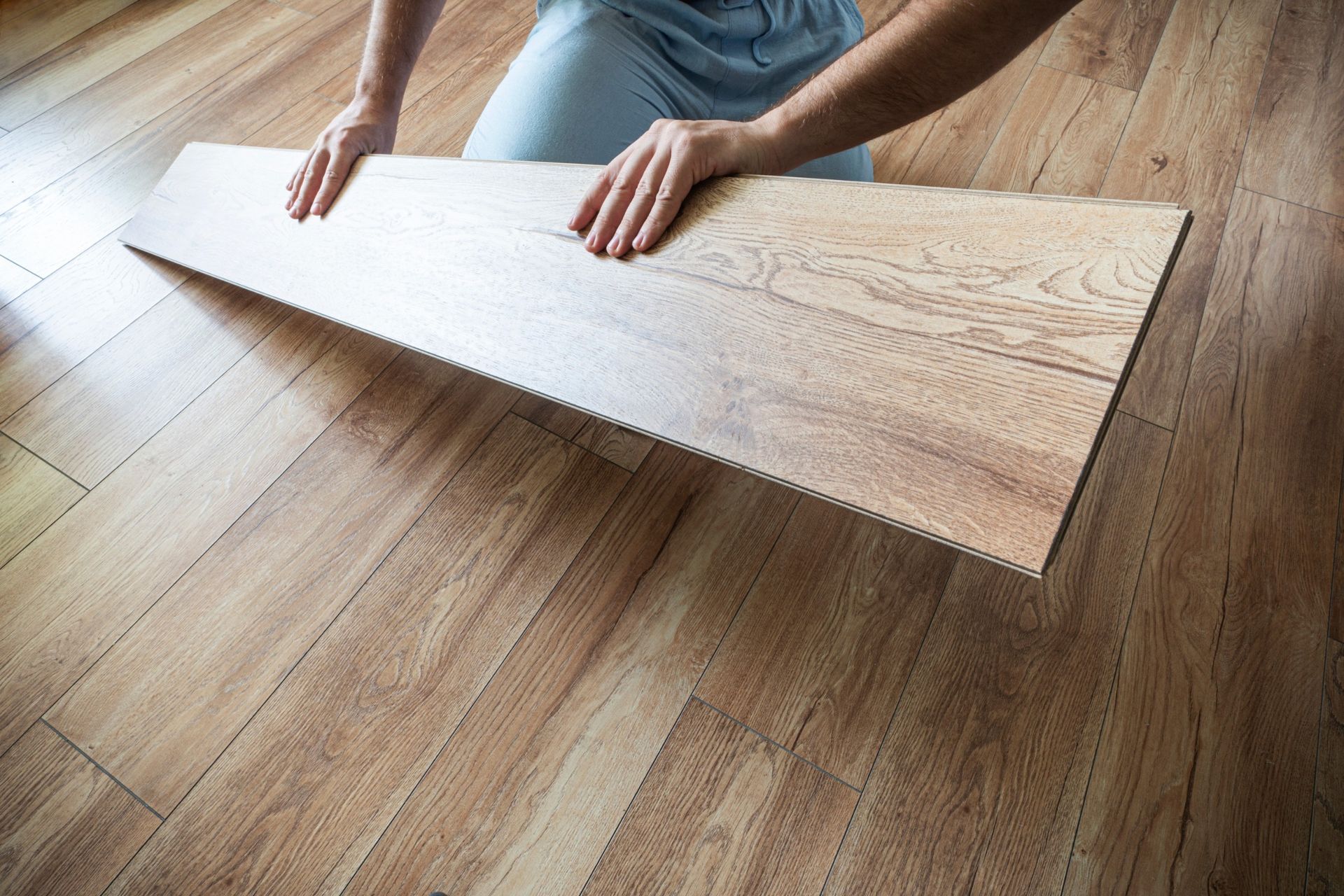 Una persona está colocando un trozo de madera sobre un piso de madera.