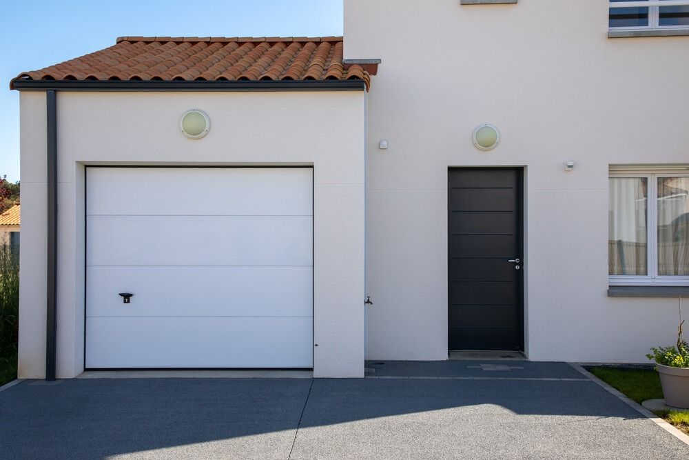 Una casa con una puerta de garaje blanca y una puerta negra