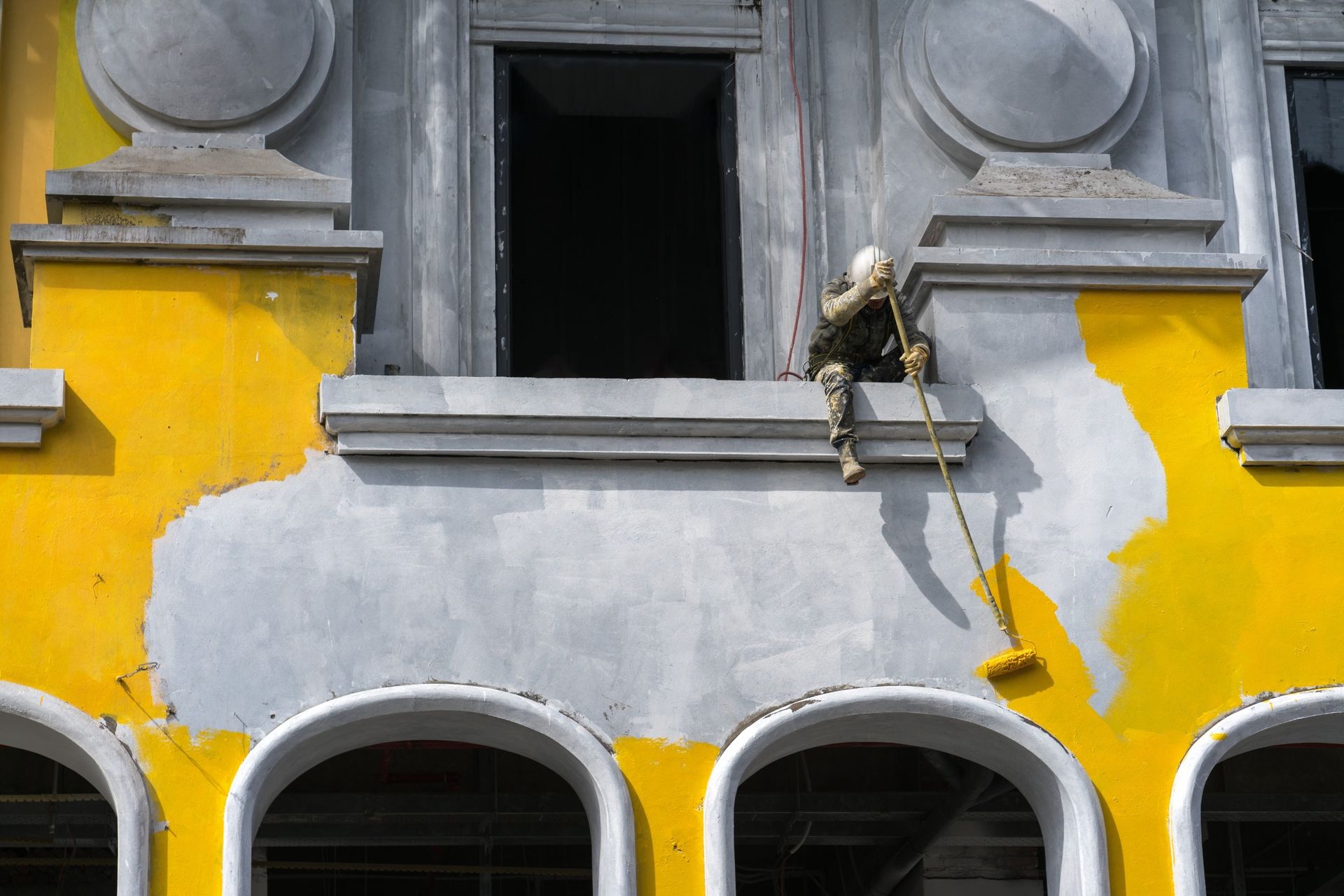 Un hombre está pintando el costado de un edificio con un rodillo.