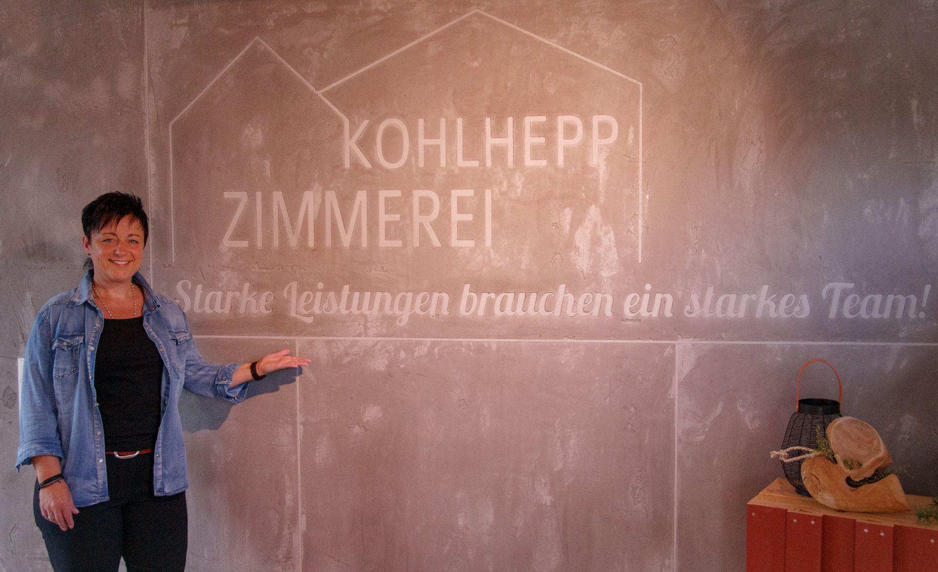 Frau steht vor Firmenname auf einer Wand