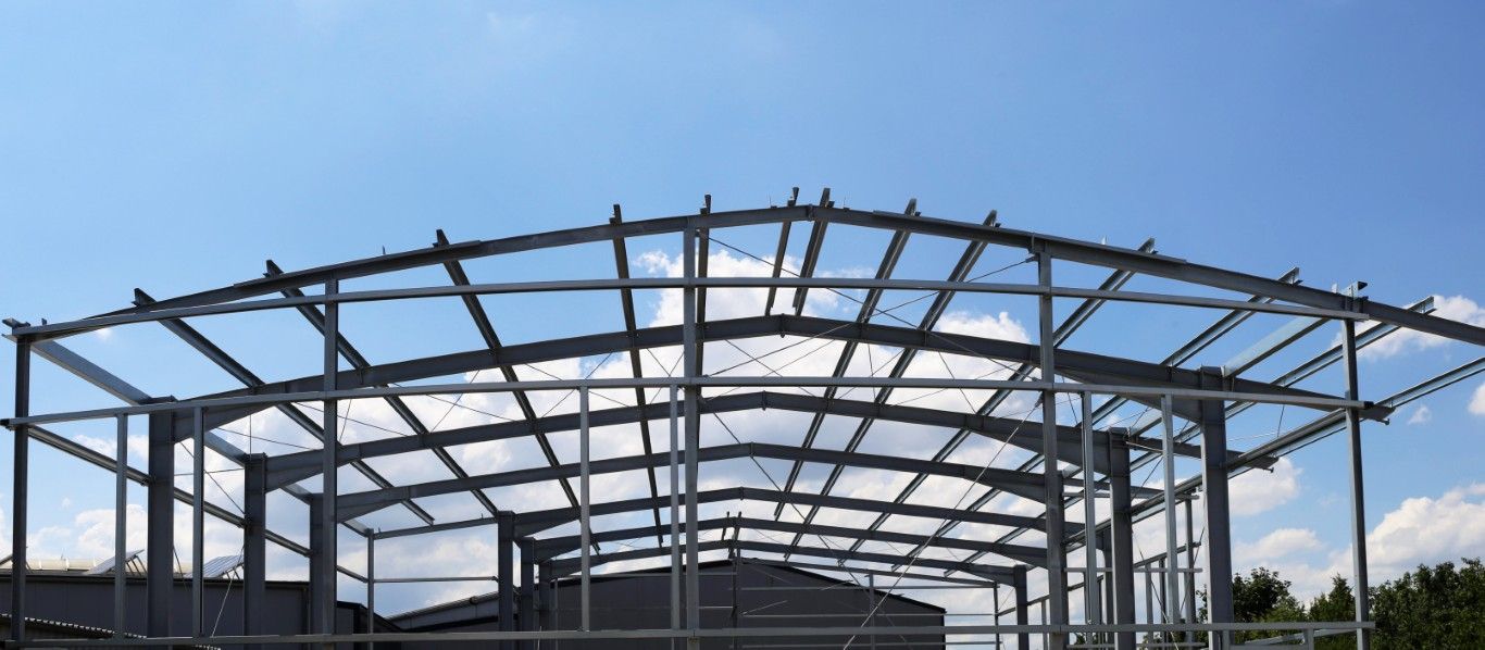 Stahlrahmen eines im Bau befindlichen Gebäudes vor blauem Himmel mit Wolken.