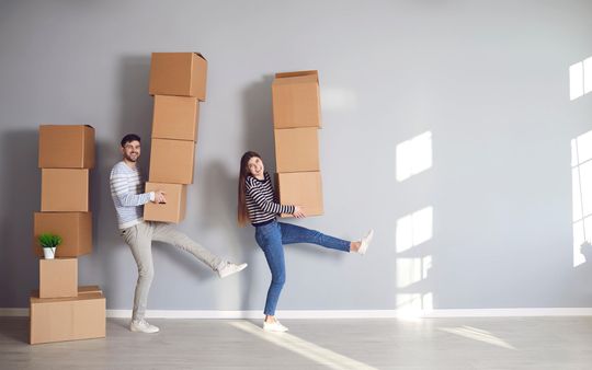 Un homme et une femme portent des cartons dans une pièce.