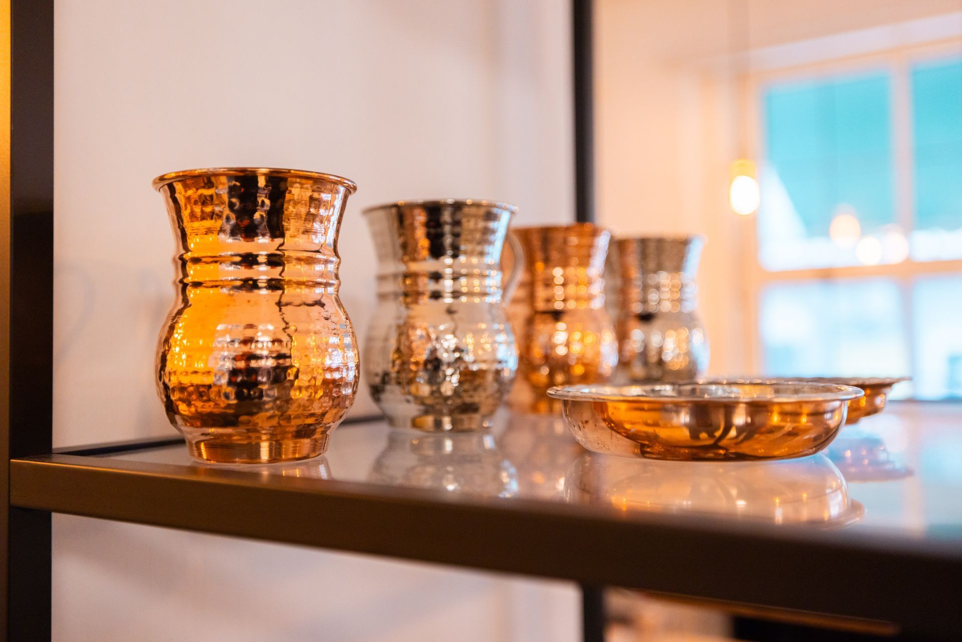Restaurantinterieur mit Holztischen und gemusterten Stühlen, grünem Laub an der Decke und heller Beleuchtung.
