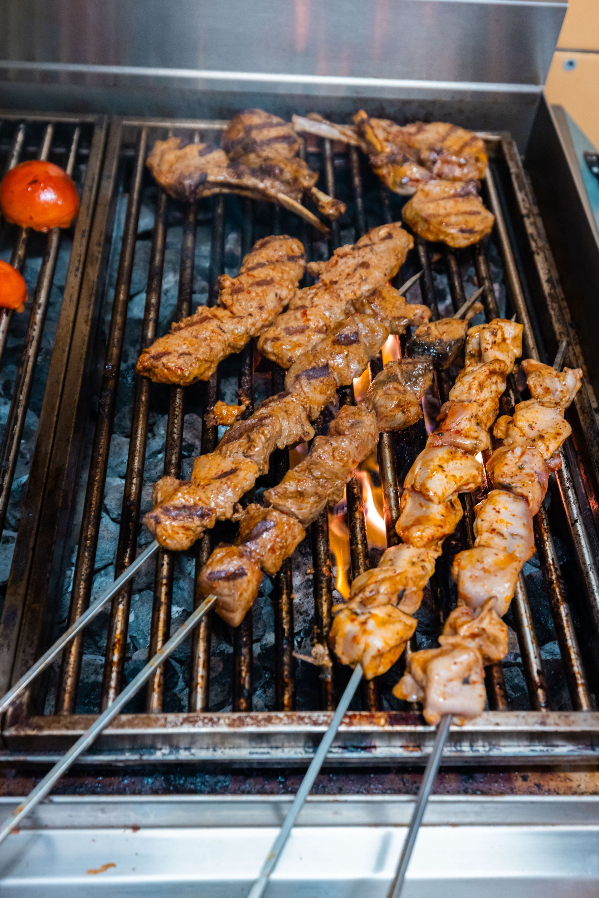 Restaurantinterieur mit Holztischen und gemusterten Stühlen, grünem Laub an der Decke und heller Beleuchtung.