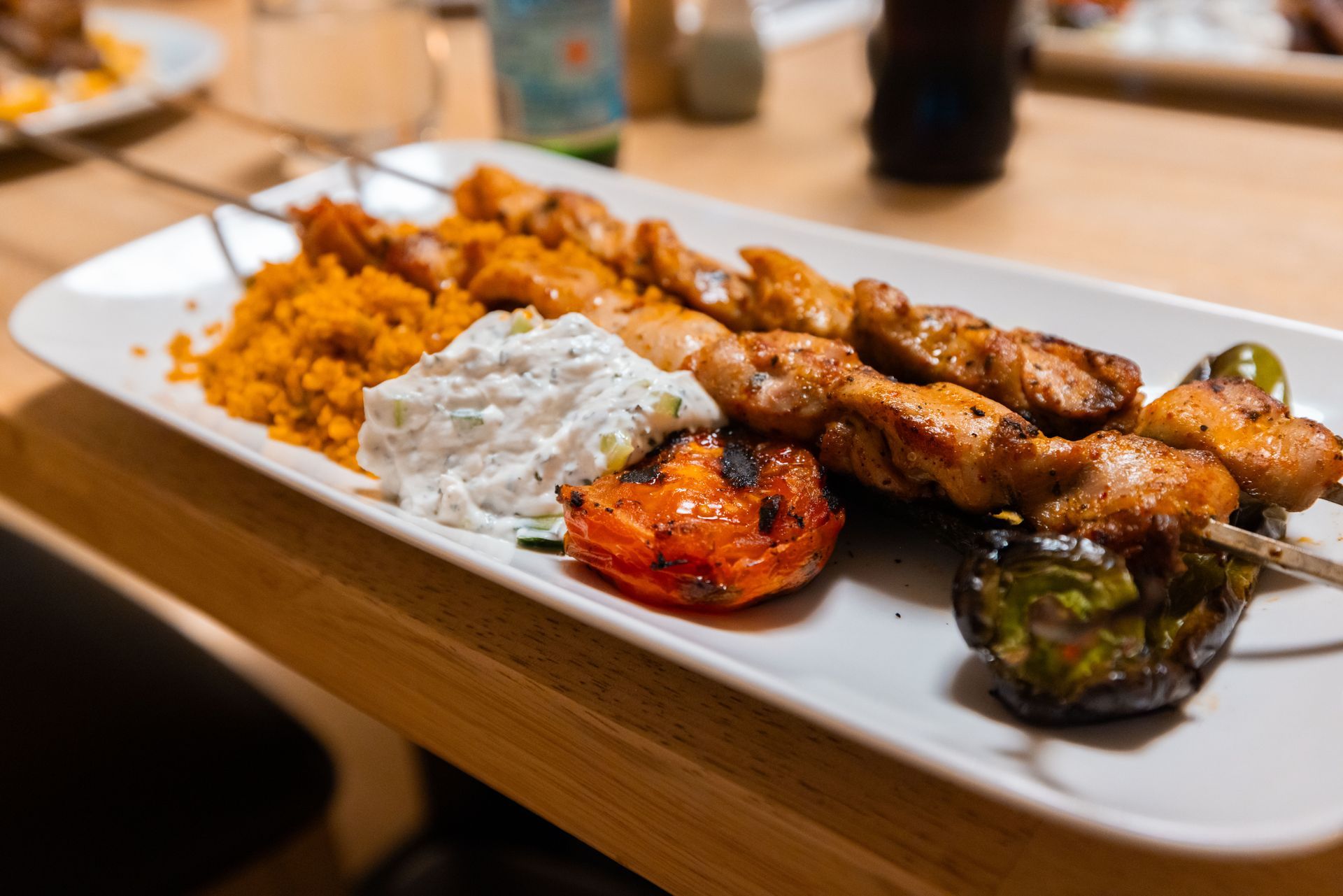 Restauranttische mit Gläsern, Tellern und Besteck. Gedämpftes Licht, verschwommener Hintergrund.