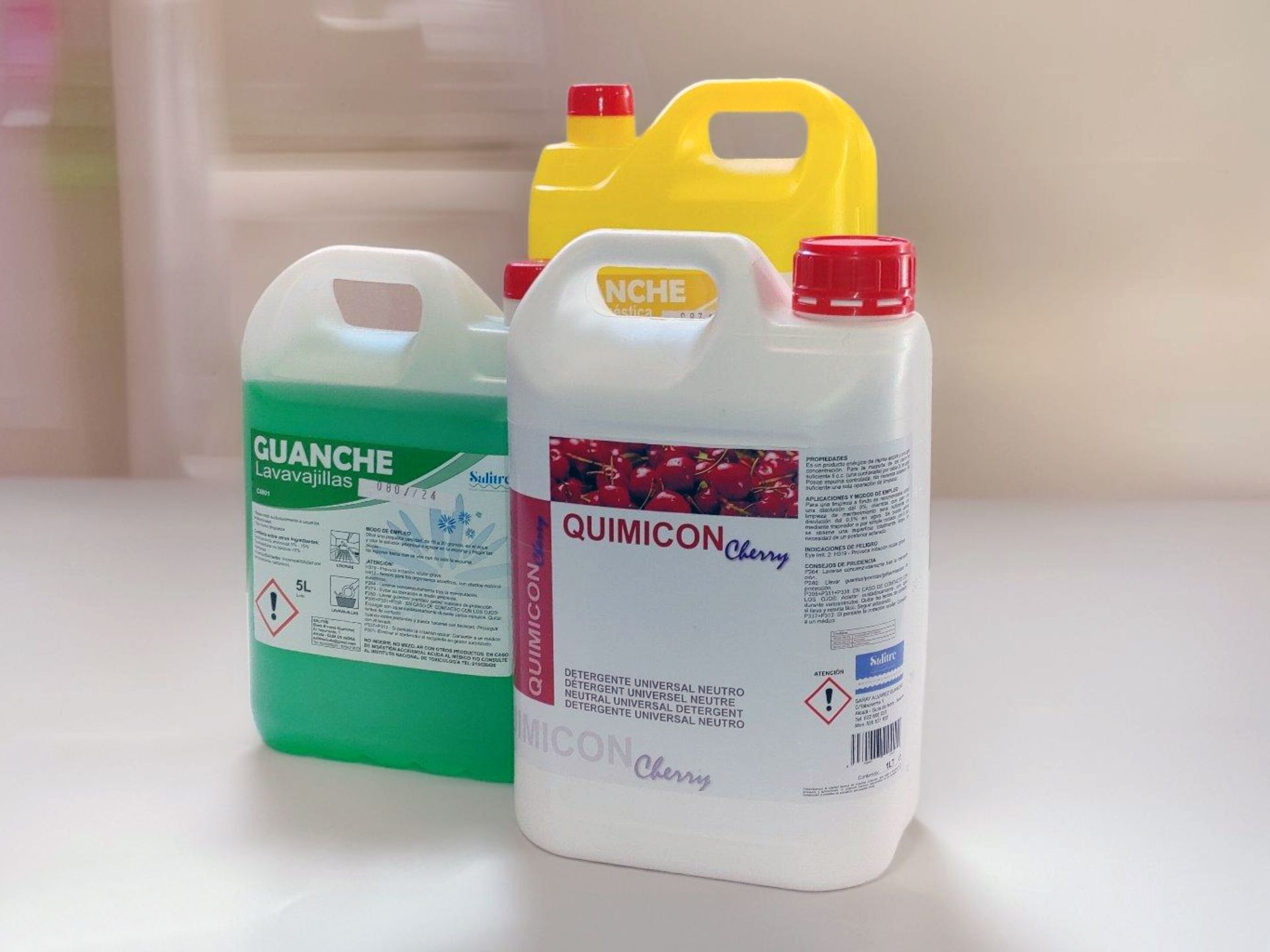Tres botellas de productos de limpieza están apiladas una encima de otra sobre una mesa.