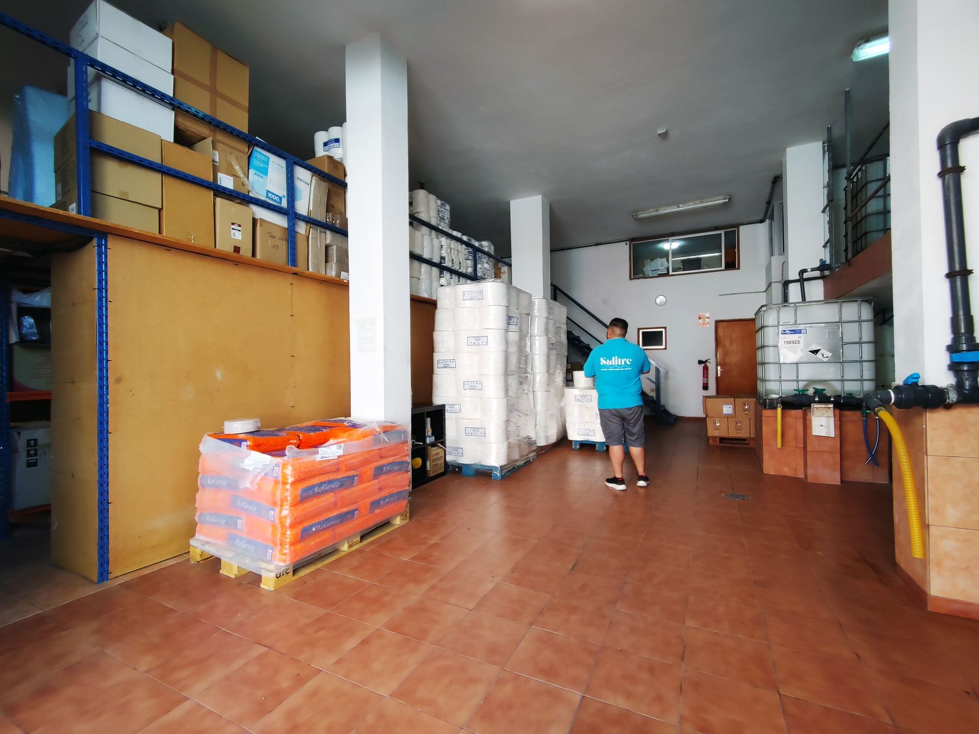 Un hombre con una camisa azul está parado en un gran almacén.