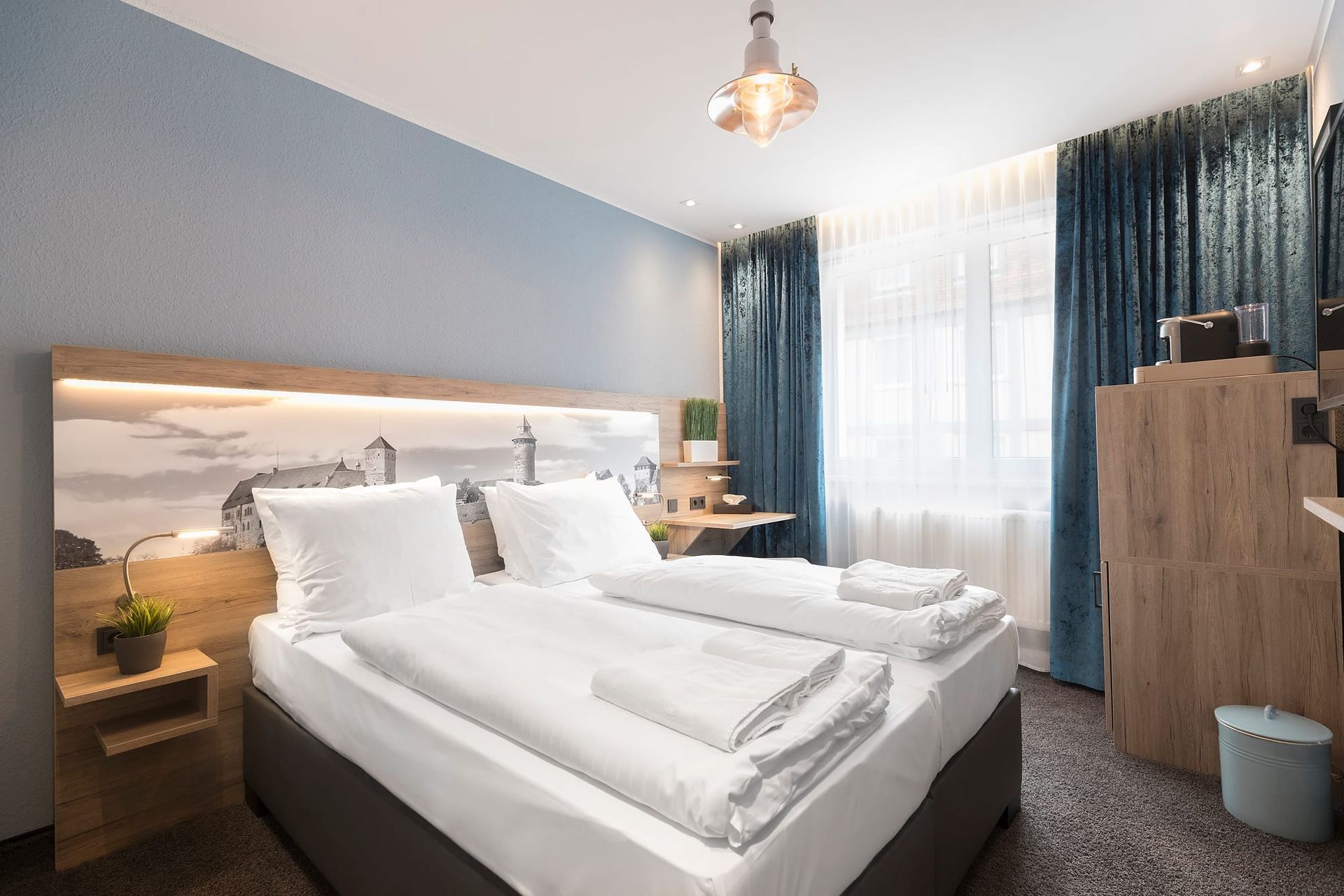 Ein Hotelzimmer mit zwei Betten und blauen Vorhängen