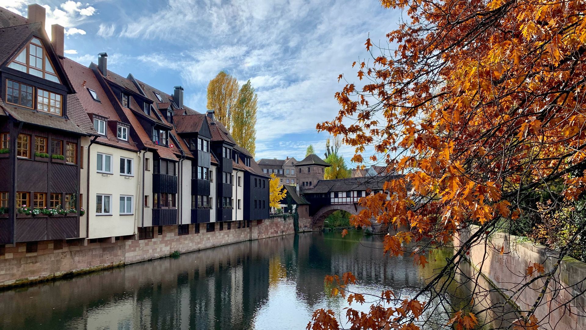 Eine Häuserreihe entlang eines Flusses mit einer Brücke im Hintergrund