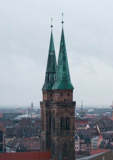 Eine Luftaufnahme einer Kirche mit zwei grünen Türmen in einer Stadt.