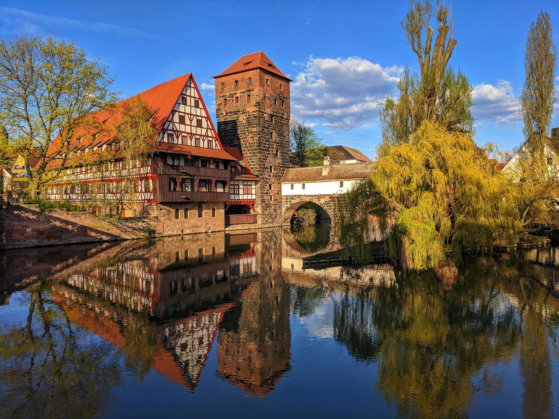Ein Gebäude mit einem roten Dach spiegelt sich in einem Gewässer