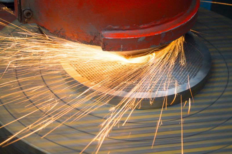 Eine Maschine schleift ein Stück Metall, wobei Funken austreten.