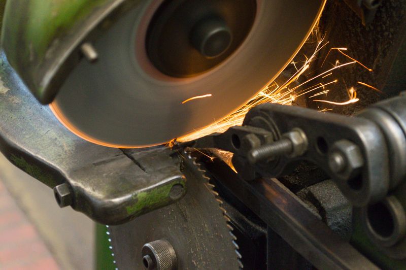 Eine Maschine schneidet ein Stück Metall, wobei Funken entstehen.