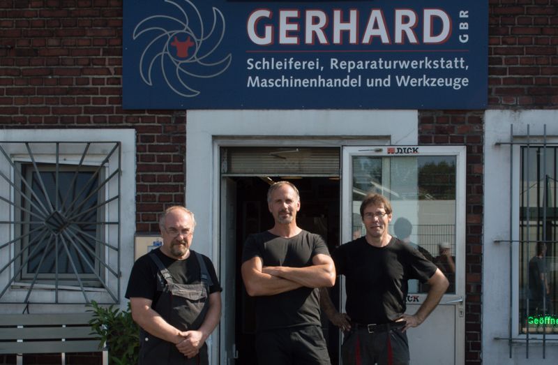 Drei Männer stehen vor einem Gerhard-Schild