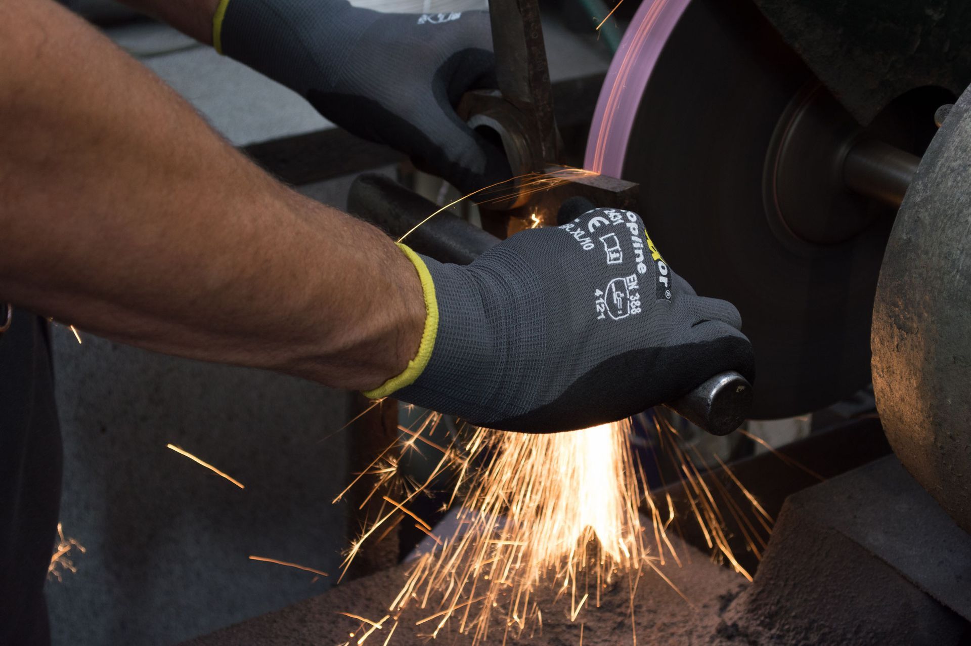 Eine Person mit Handschuhen schleift ein Stück Metall