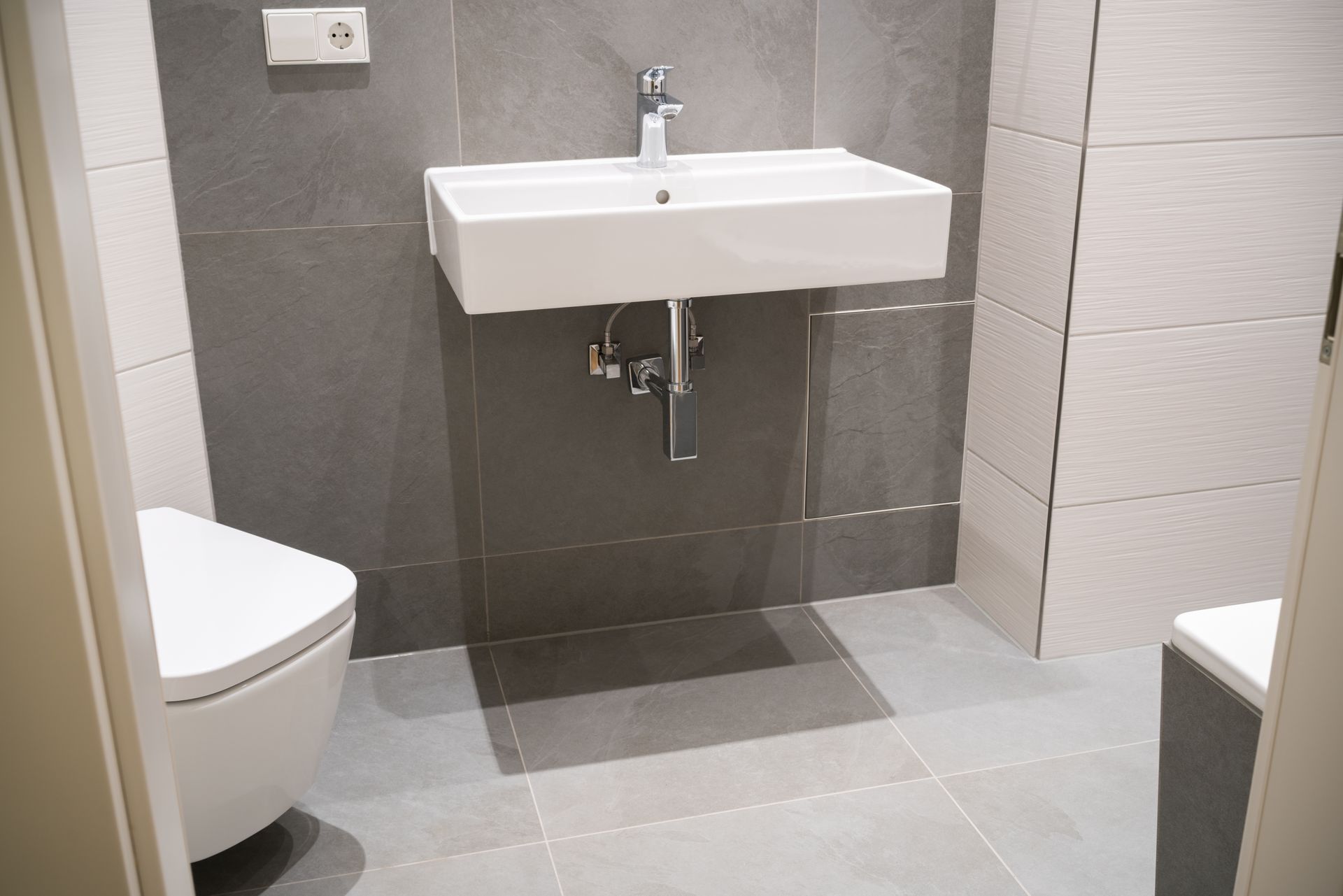 Des toilettes à gauche d'une vasque dans une salle de bains.
