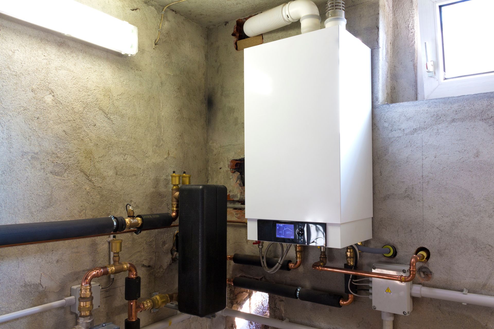 Chauffe-eau thermodynamique accroché sur un mur en pierre.