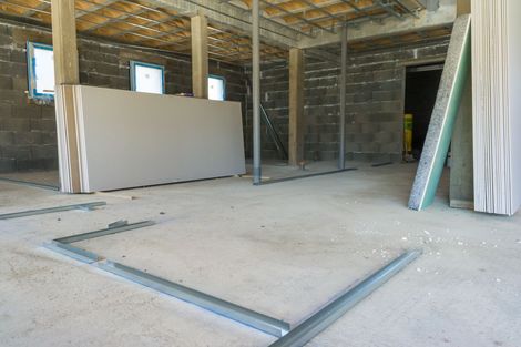 Chantier de construction intérieur avec cloisons sèches et ossature métallique. Sol en béton, murs en parpaings et plafond non fini.