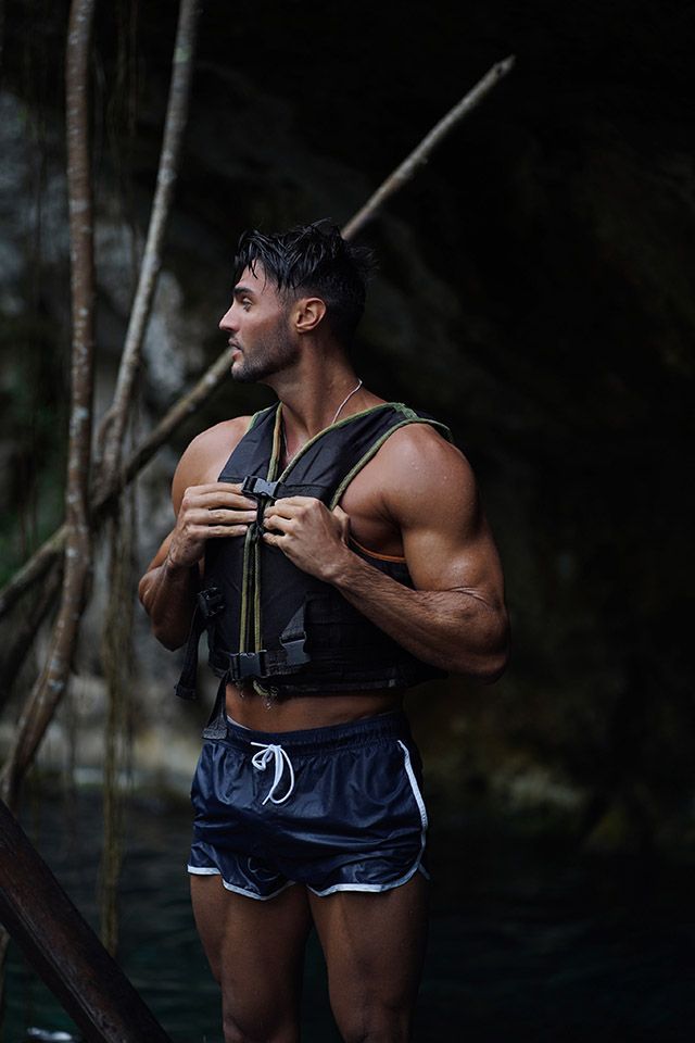 Ein Mann mit Schwimmweste und Shorts steht im Wasser.