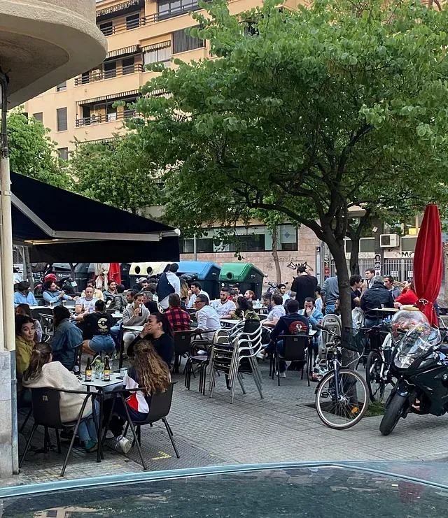 Un grupo de personas están sentadas en mesas afuera de un restaurante.