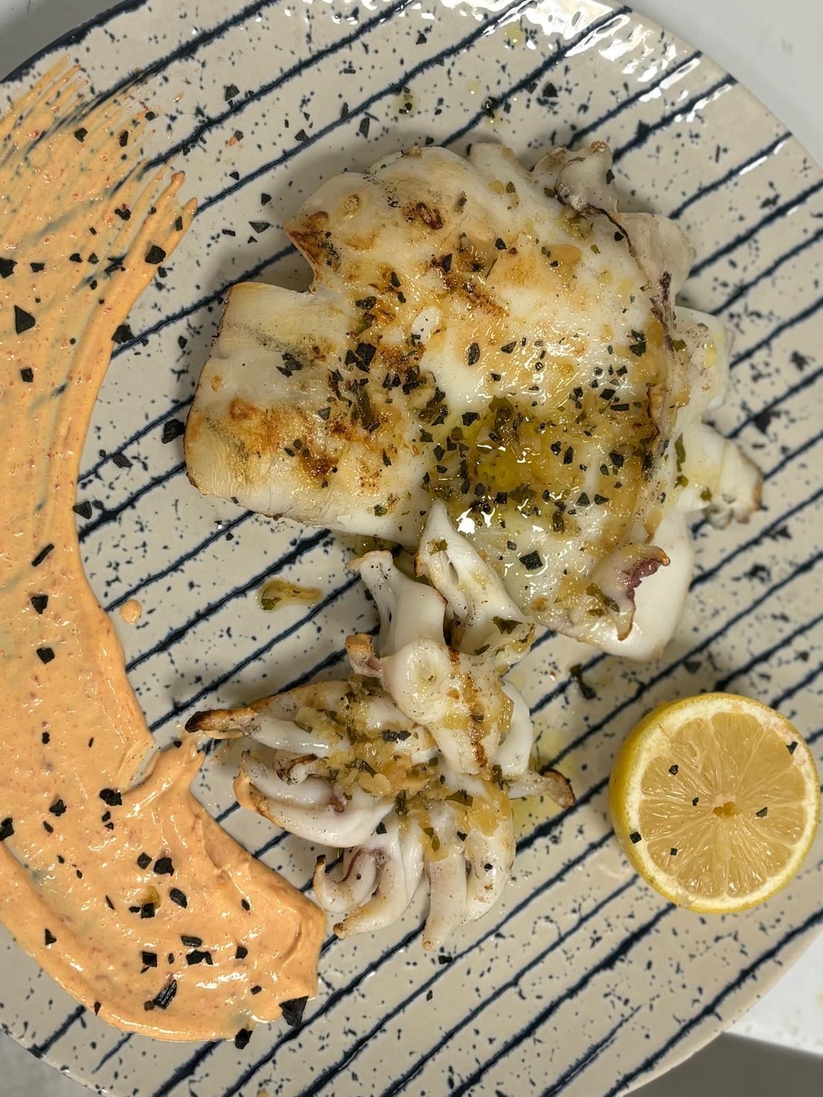 Un plato de comida con salsa y un limón encima.