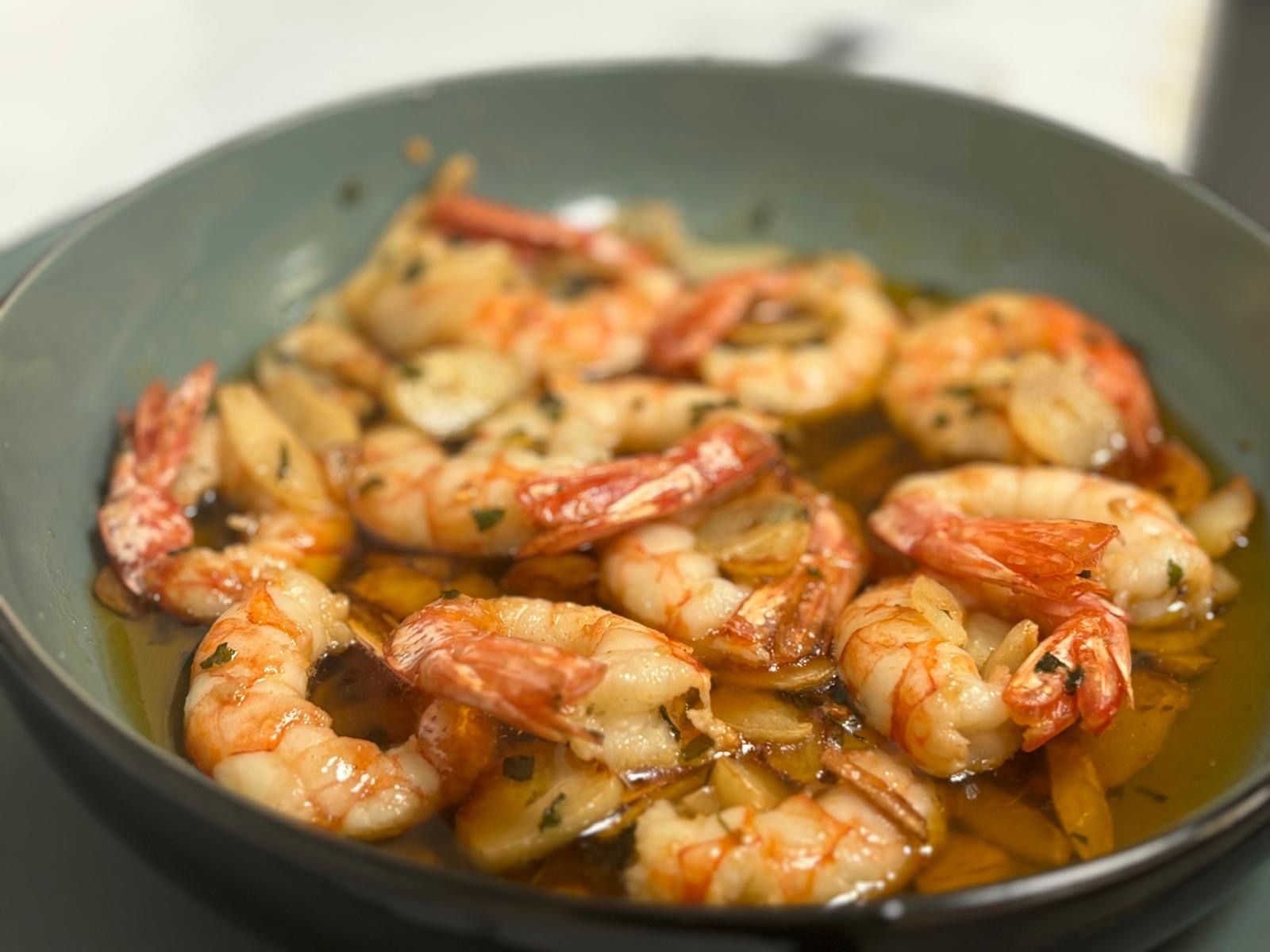 Un primer plano de un tazón de camarones en salsa.
