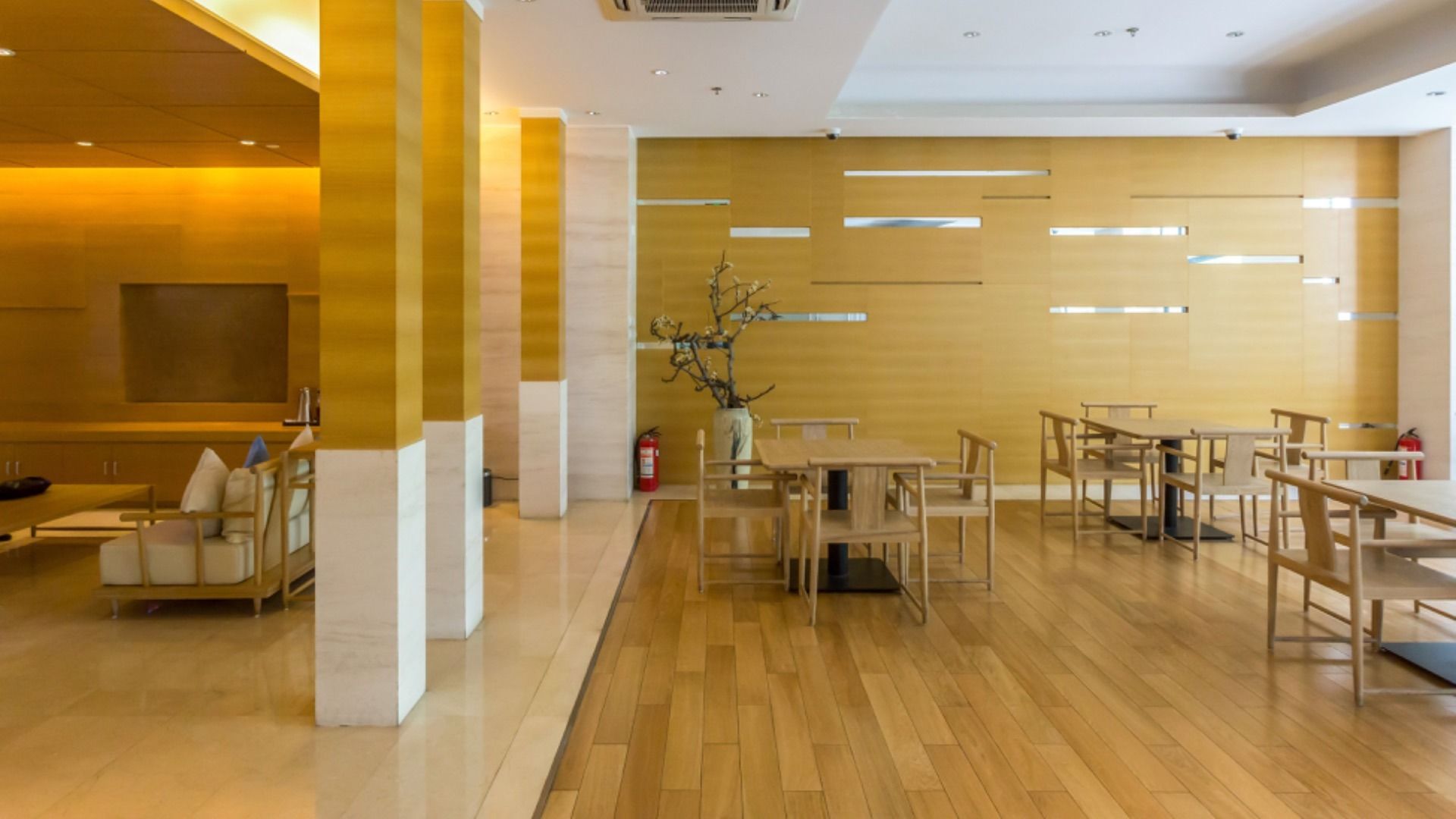 Una habitación grande con suelos de madera, mesas y sillas.