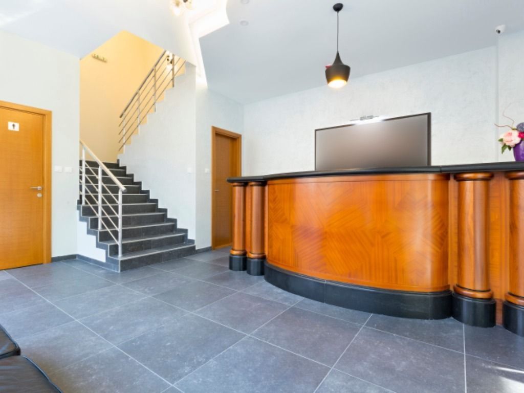 Un área de recepción con un escritorio de madera y escaleras al fondo.
