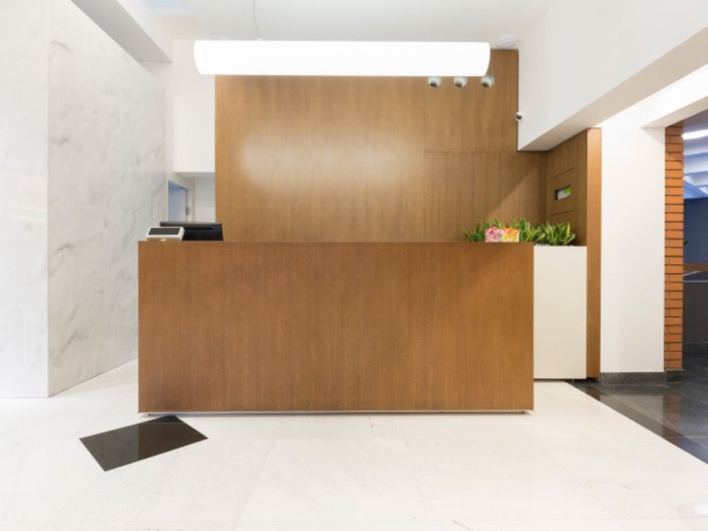 Un área de recepción con un mostrador de madera y una pared blanca.