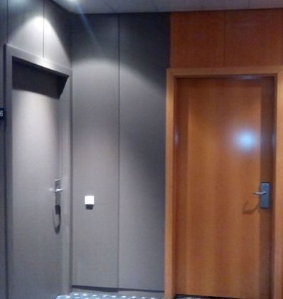 Un pasillo con una puerta de madera y una pared gris.