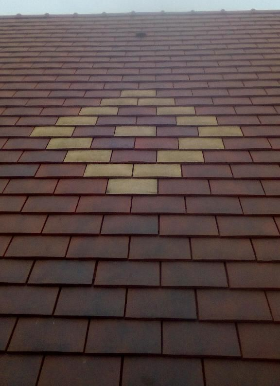 Toiture en tuiles brunes et jaunes à motif losange.