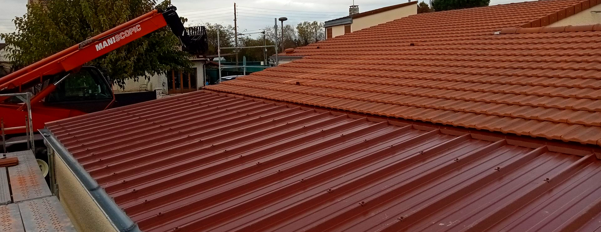 Bardage beige sur le pignon d'une maison avec un volet blanc, sur fond de ciel bleu.