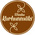 Ruskea pyöreä logo, jossa kermanvärinen teksti ”Vanha Karhunmäki” ja kukkaisia viivapiirroksia