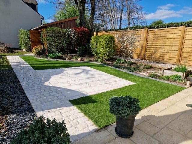 Un jardin avec les arbustes taillés et la pelouse tondue.