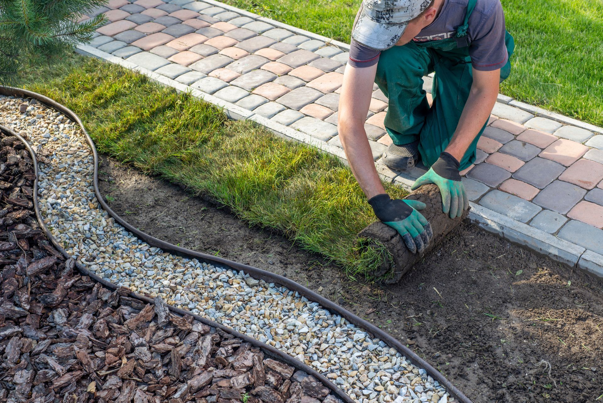 Un jardinier pose du gazon en rouleau près d'une allée.