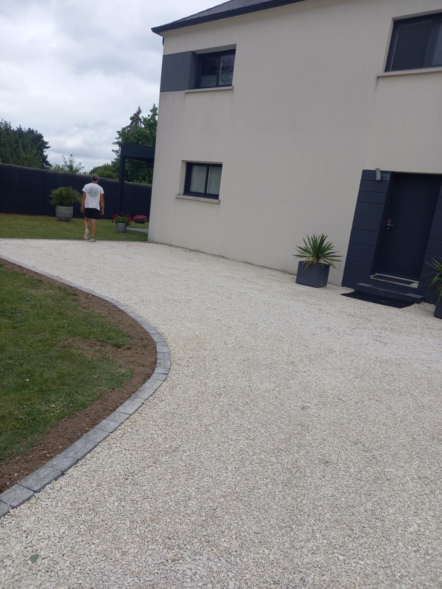 Une allée de maison en courbe avec du gravier blanc.