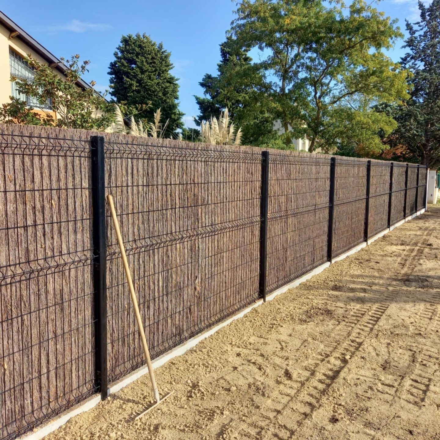 Un clôture en grillage habillée de brande de bruyère.