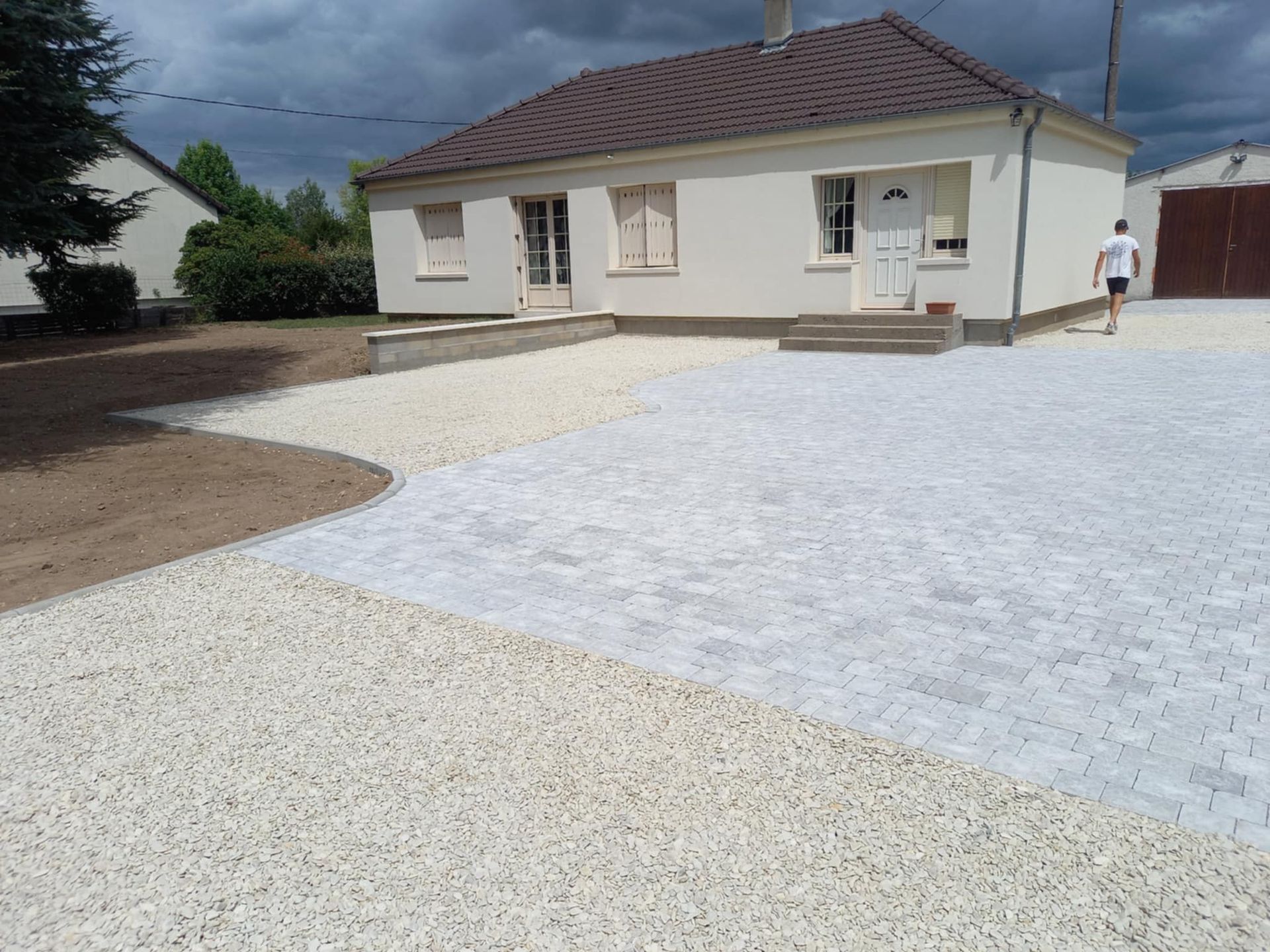 Une maison avec muret et bordures pour délimiter le jardin.