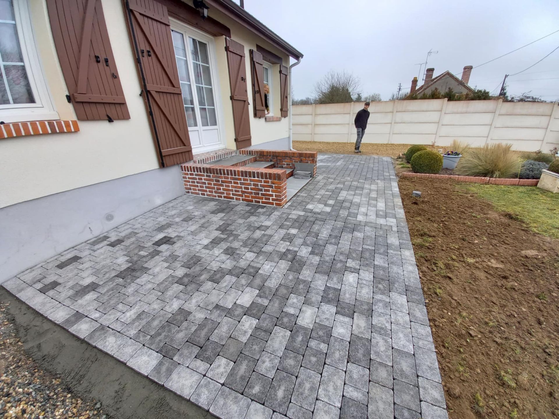 Réalisation d'un espace pavé à l'arrière d'une maison.