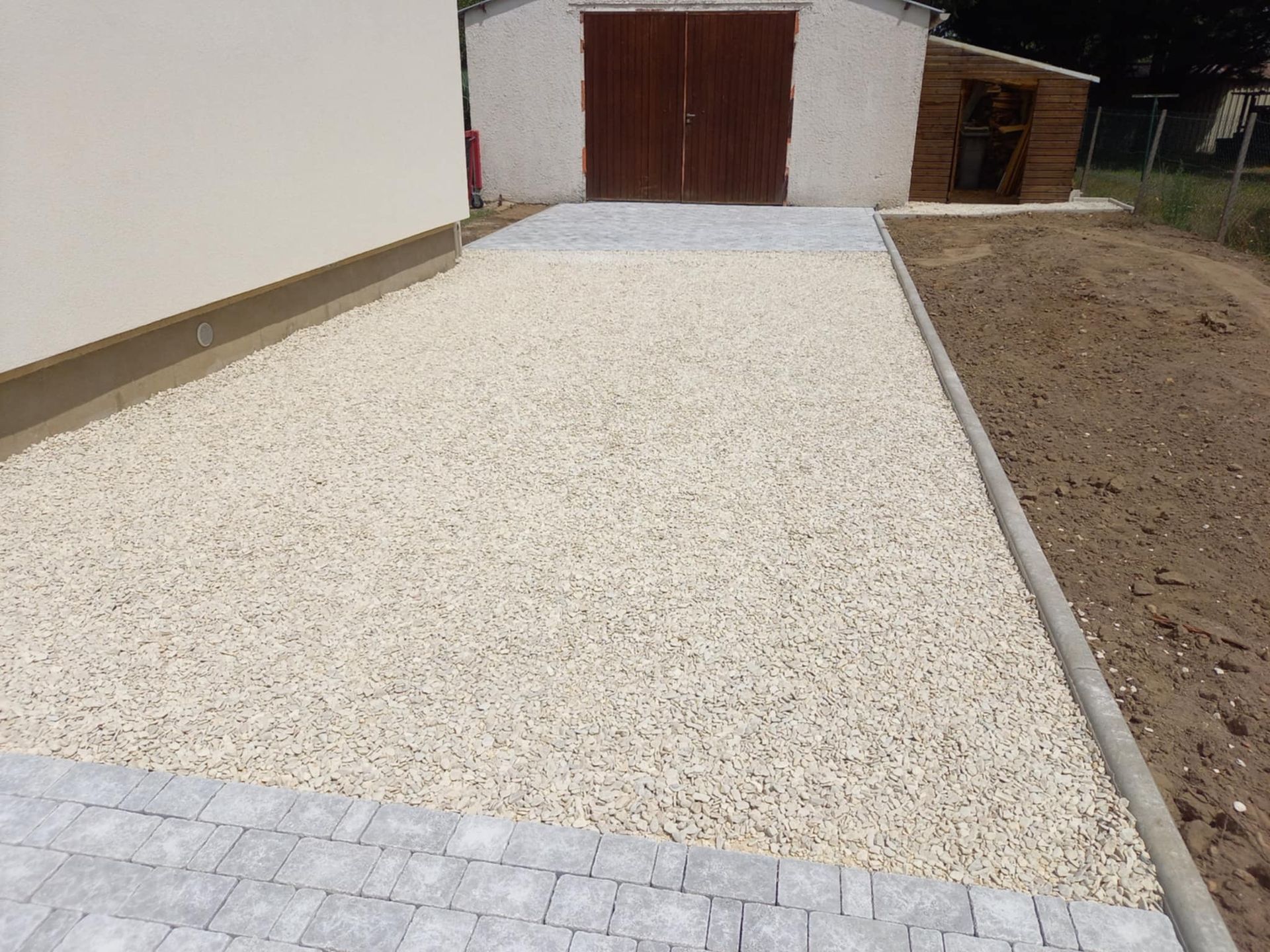 Une bordure délimite l'allée en calcaire du jardin en terre.