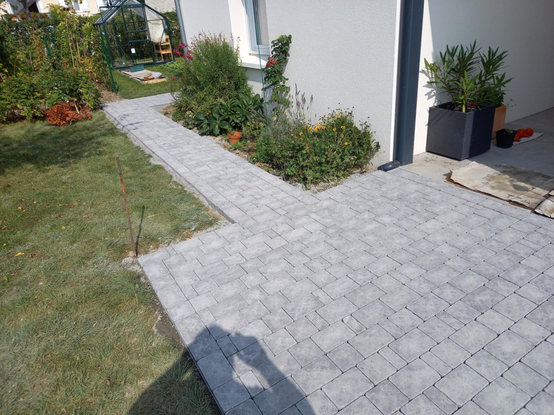 Une allée et un tour de maison en pavage gris.