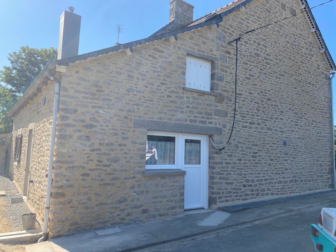Extérieur d'une maison en pierre avec porte et fenêtre.