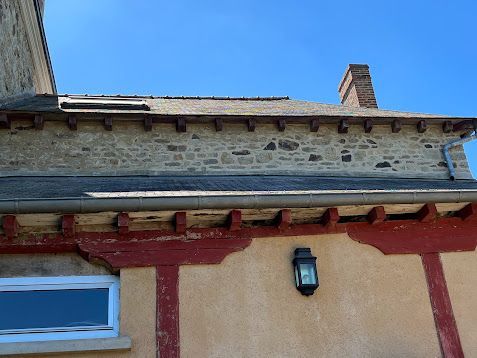 Gros plan sur la façade d'un bâtiment en stuc avec des ornements, une fenêtre et une lanterne murale.