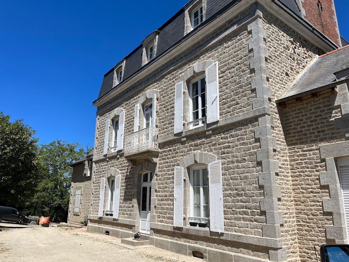 Maison en pierre aux volets et au toit.