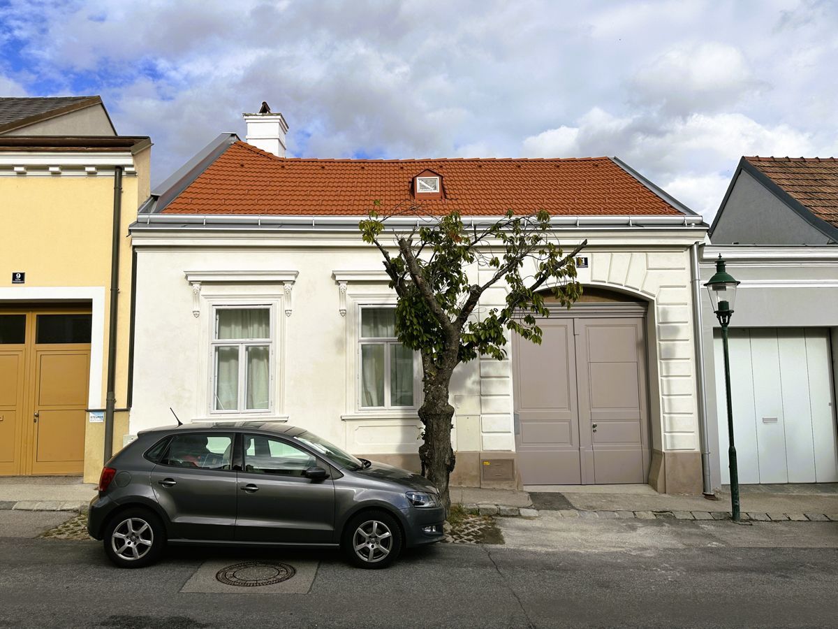 Ein weißes Haus mit einem braunen Dach und einem Holzzaun
