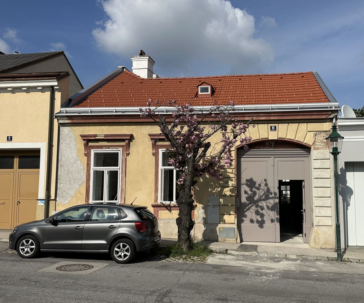 Ein weißes Haus mit einem braunen Dach und einem Holzzaun