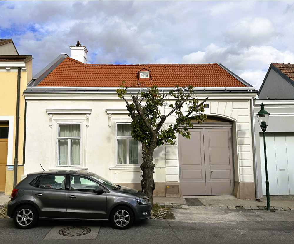 Ein weißes Haus mit einem braunen Dach und einem Holzzaun