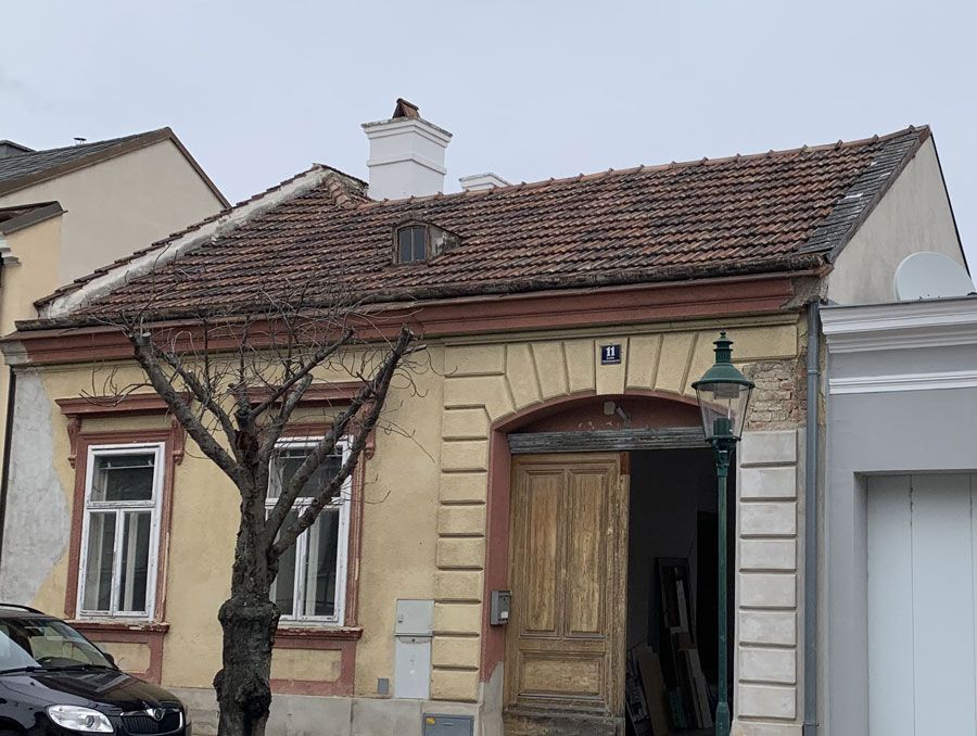 Ein weißes Haus mit einem braunen Dach und einem Holzzaun