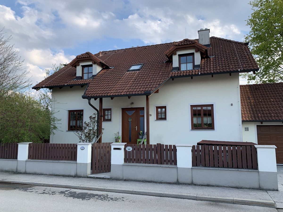 Ein weißes Haus mit einem braunen Dach und einem Holzzaun
