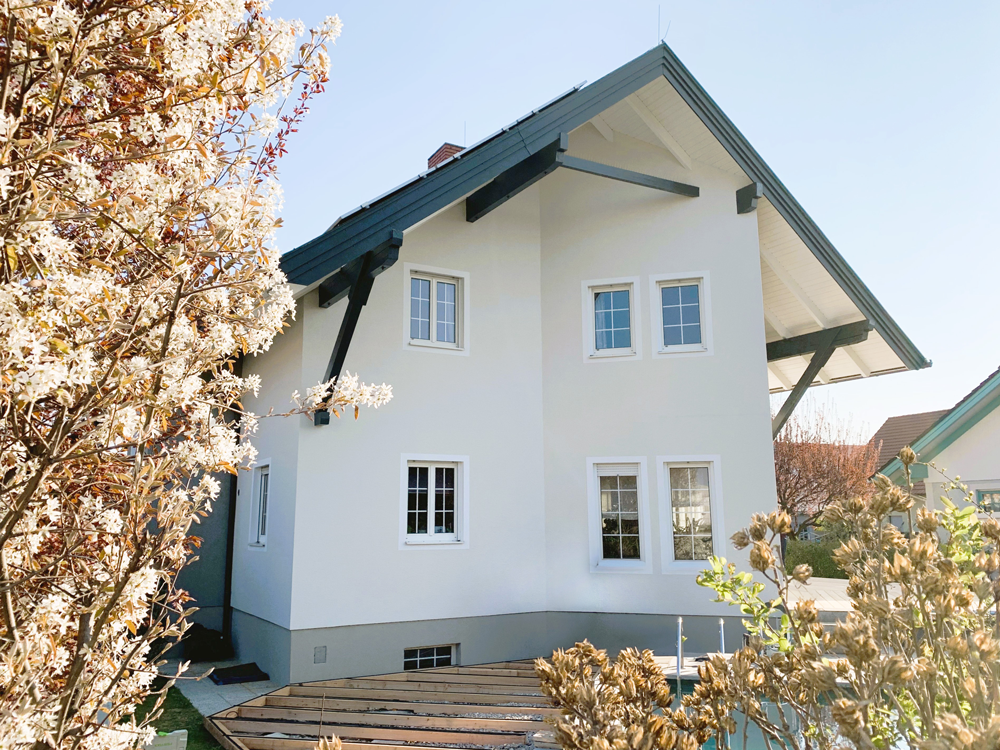 Ein Mann steht vor einem weißen Haus mit einem schwarzen Dach.